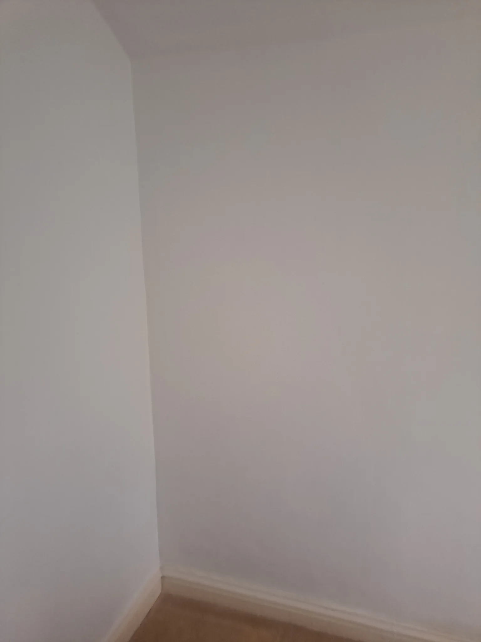 The same wall corner after damp treatment and replastering, cleanly painted with no trace of mould