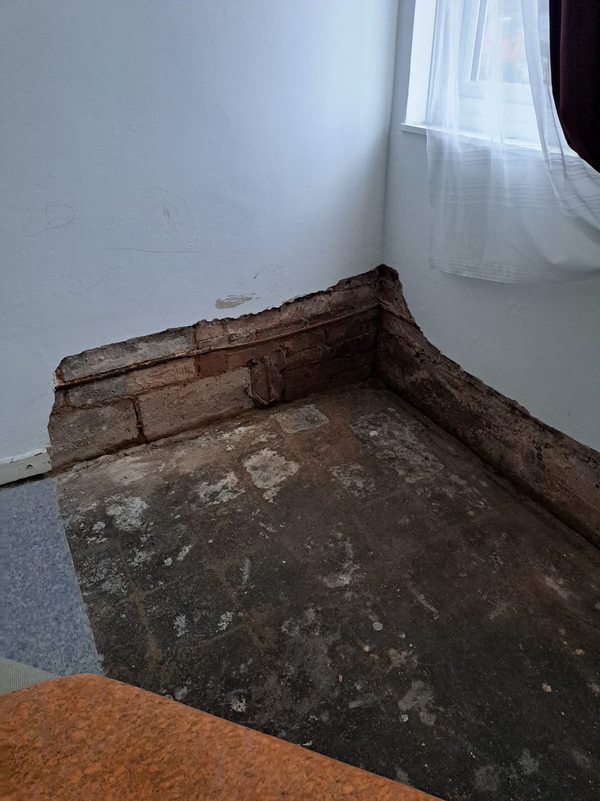 Room with flooring removed, exposing the sub-floor and brickwork around the perimeter